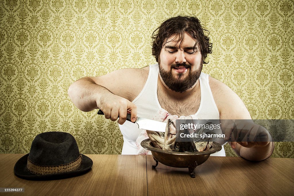 Grand gros homme manger la soupe de poisson de la tête sur une table en bois