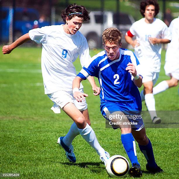 male soccer player challenges another player for ball from behind - tackle stockfoto's en -beelden