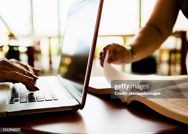 computer and book in library - hand turning page stock pictures, royalty-free photos & images