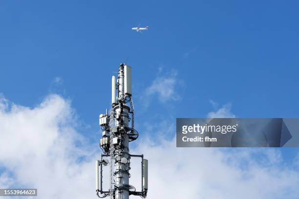 mobile phone transmitter mast with aircraft in the sky - repeater tower stock-fotos und bilder