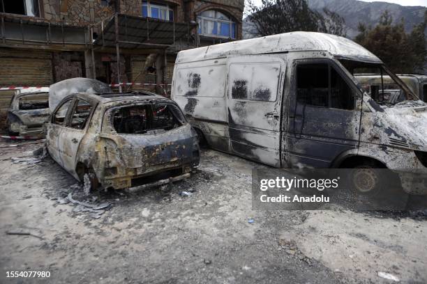 Heavily damaged vehicles are seen as deadly wildfires ravage settlements along the country's Mediterranean coast and firefighters continue their...