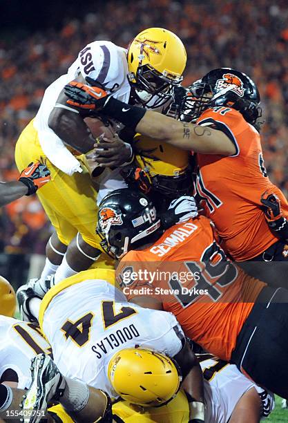 Running back Cameron Marshall of the Arizona State Sun Devils leaps over the goal line for a touchdown as defensive tackle Andrew Seumalo and...