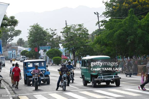 Old American cars and motorcycles drive along a street in Santiago de Cuba on July 25 on the eve of the country's national day. The Cuban government...
