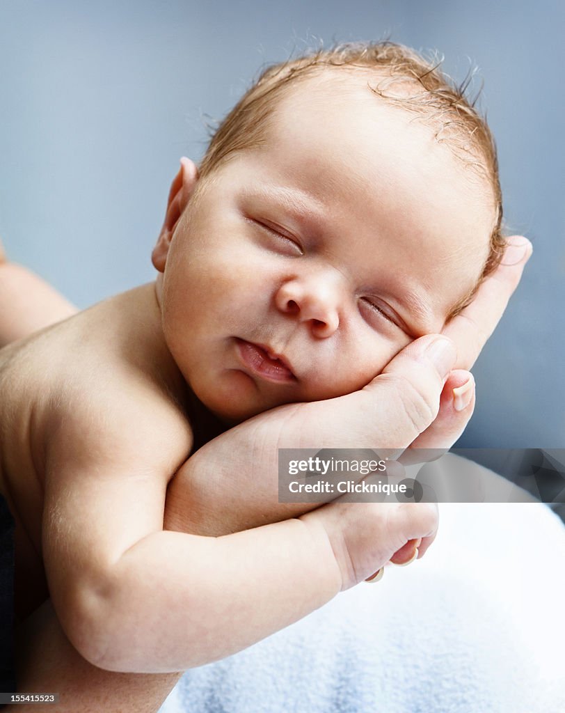 Blissfully sleeping baby cradled in mothers hands