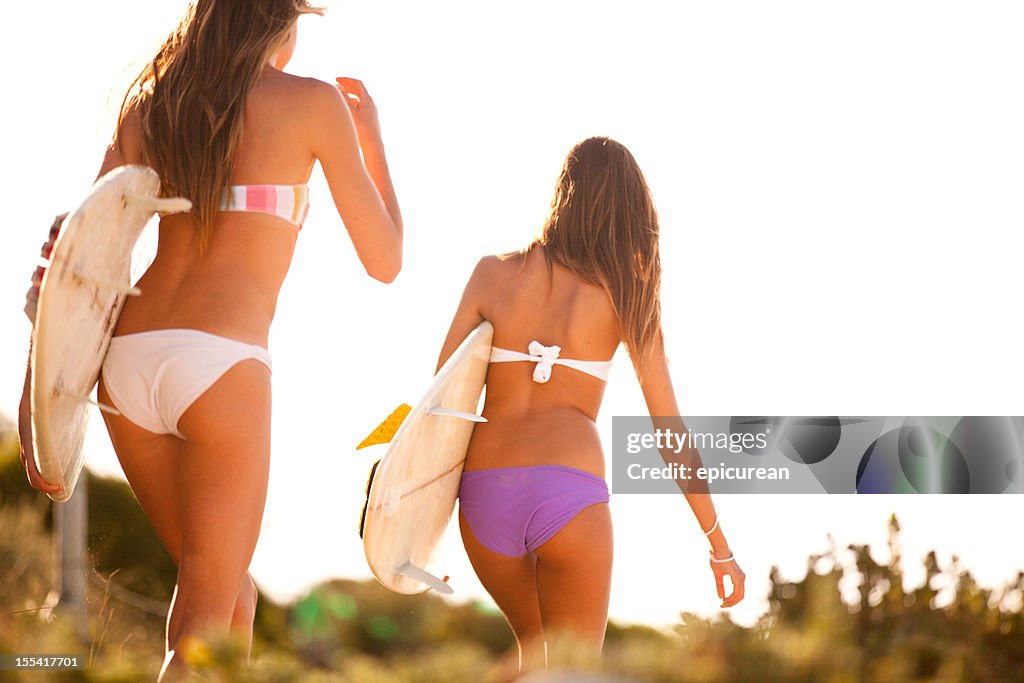 Two beautiful healthy young women going for a surf together