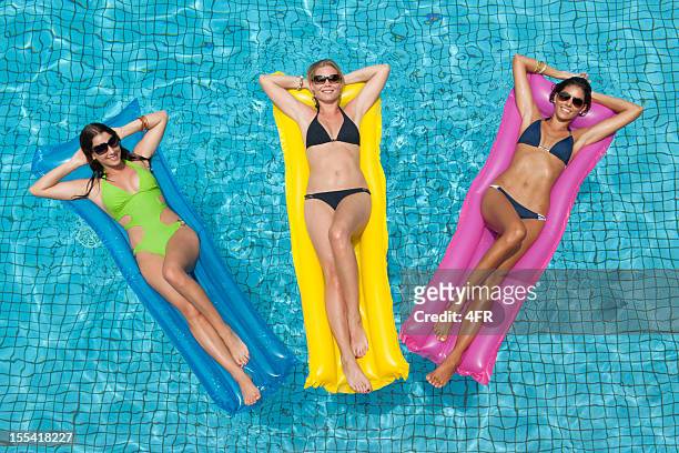 drei schöne frauen sonne baden im swimmingpool (xxxl) - luftmatraze stock-fotos und bilder