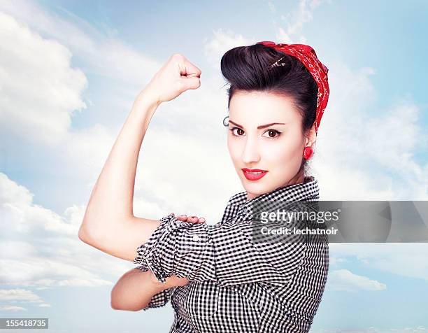 brunette beeindruckende berühmten rosie riveter-pose - rolling up sleeve stock-fotos und bilder