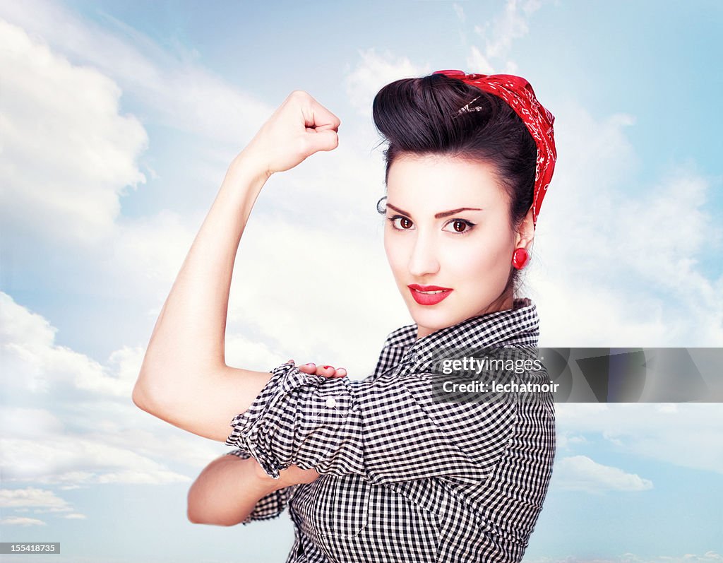 Brunette striking a famous Rosie Riveter pose