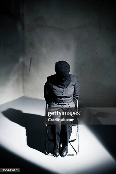 prisoner tied to chair in cell spotlight - tortue stock pictures, royalty-free photos & images