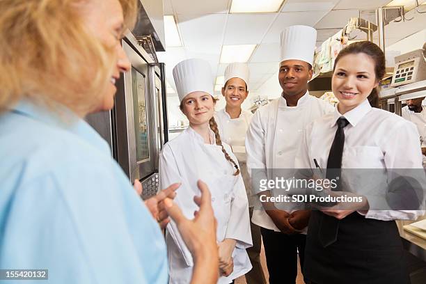 restaurant manager giving instructions to team of chefs and waitress - servitris bildbanksfoton och bilder