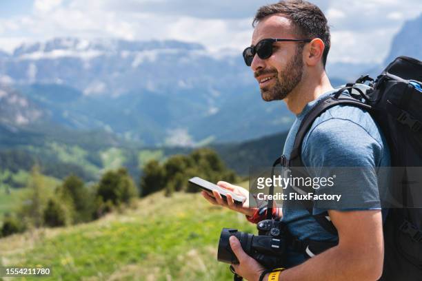 male hiker using mobile phone, while admiring the view of dolomites - smartphone camera stock pictures, royalty-free photos & images