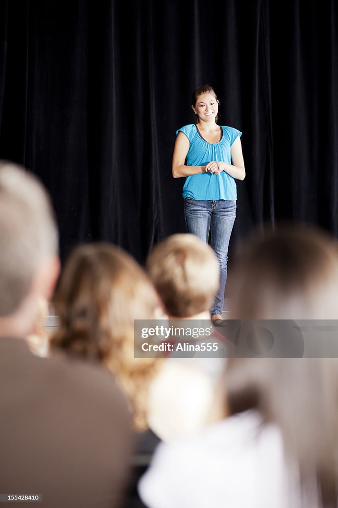 Teenage girl delivering a speech on stage for an audience