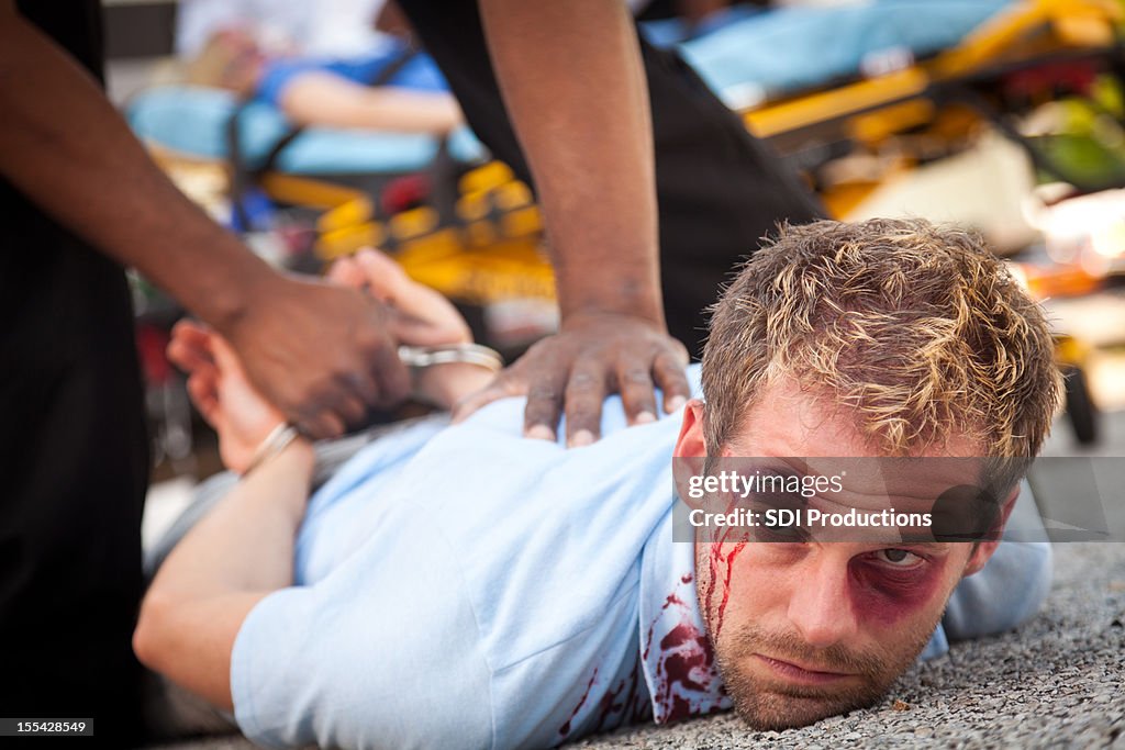 Injured man being forced down and arrested
