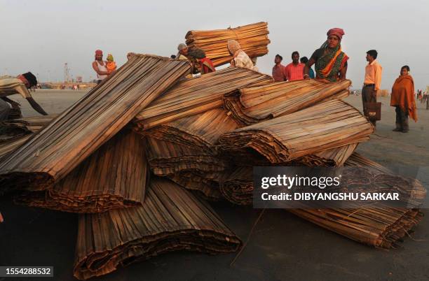 Indian labourers arrange straw mats before delivering to the temporary camps at the Gangasagar some 155 Kms south of Kolkata on January 12, 2012....