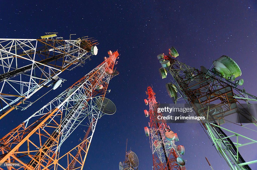 Five telecommunication towers under a night sky 