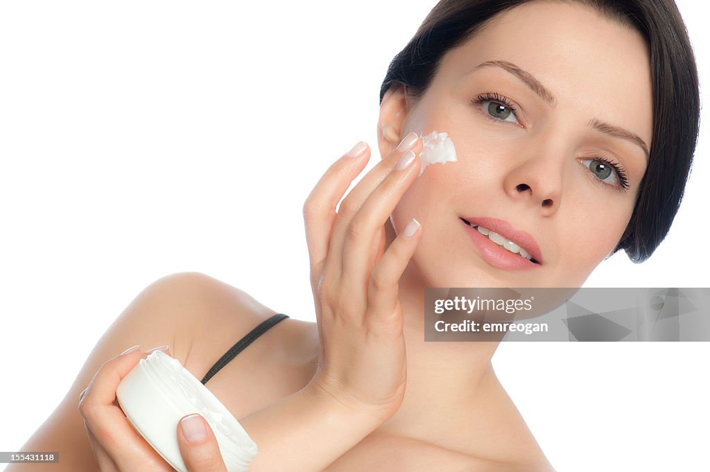 Young adult girl applying moisturiser cream