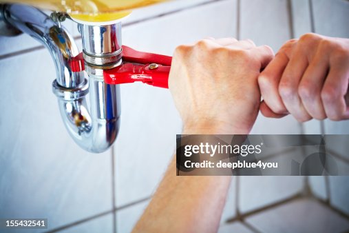 Plumber hands holding wrench and fixing a sink in bathroom Plumber hands holding wrench and fixing a sink in bathroom