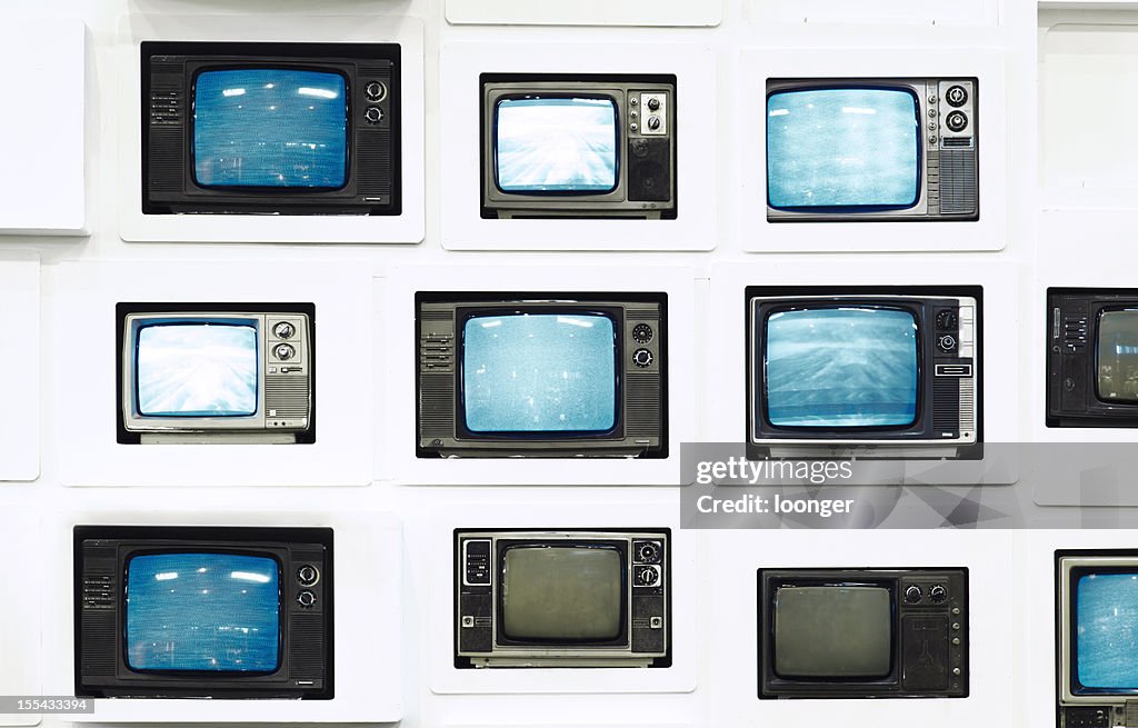 Muchos televisores vintage en antiguo de pared blanco