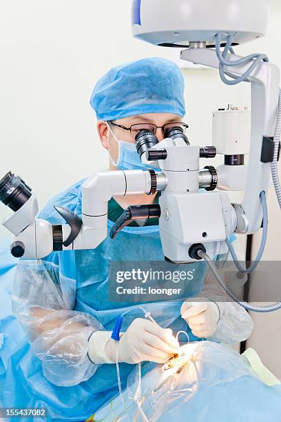 surgeon using magnifier to perform cataract surgery - microchirurgie stockfoto's en -beelden