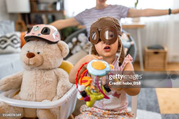 kleinkindmädchen und ihre mutter spielen piloten zu hause - rollenspiel stock-fotos und bilder