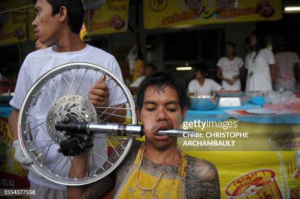 Devotee of the Chinese Bang Neow Shrine sits with a shock absorber piercing his cheek ahead of a street procession marking the annual Vegetarian...