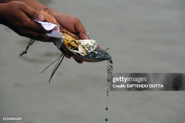 An Indian Hindu devotee holds out offerings as he performs "Tarpan", a ritual to pay obesience to ones forefathers, on the last day of "Pitrupaksh" -...