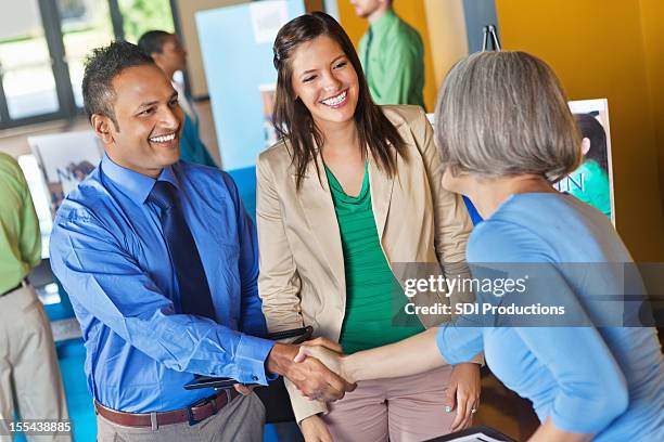 business team greeting prospective employee at job fair - job fair stock pictures, royalty-free photos & images