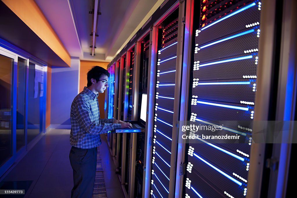 Man standing in neon light with IT servers