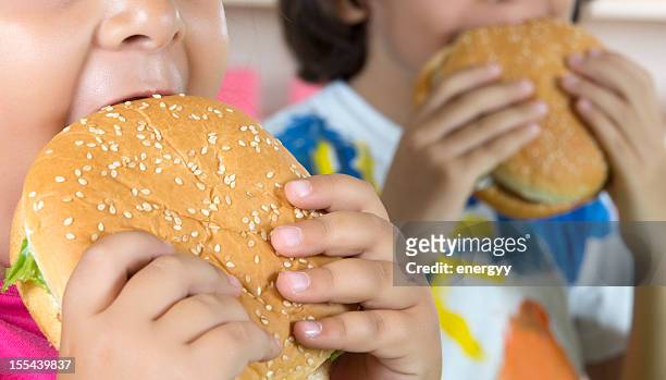 niño y niña con hamburguesas - comida rápida fotografías e imágenes de stock