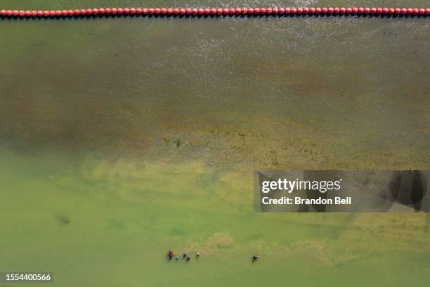 Migrants seeking asylum walk alongside buoy barriers in an attempt to cross the Rio Grande into the United States on July 18, 2023 in Eagle Pass,...