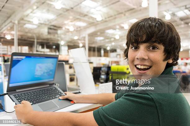 smiling teenage boy choosing a lap top - 大賣場 個照片及圖片檔
