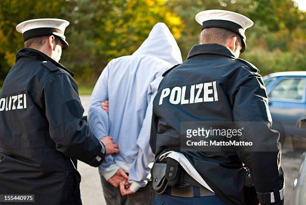 zwei polizisten sind frogmarching einem verdächtigen - polizist stock-fotos und bilder