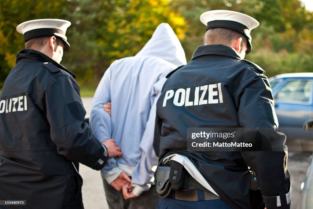 Two police officers are frogmarching a suspect