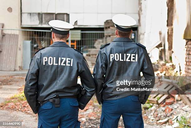 zwei polizisten sind mit dem rücken - german culture stock-fotos und bilder