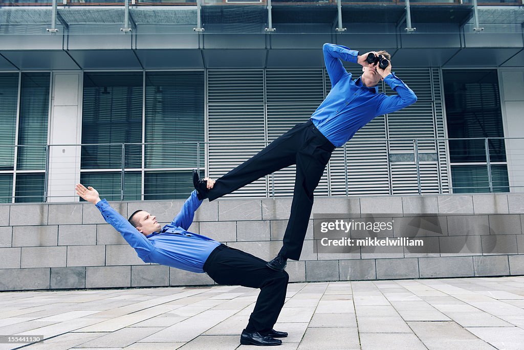 Two businessmen with acrobatic skills work together