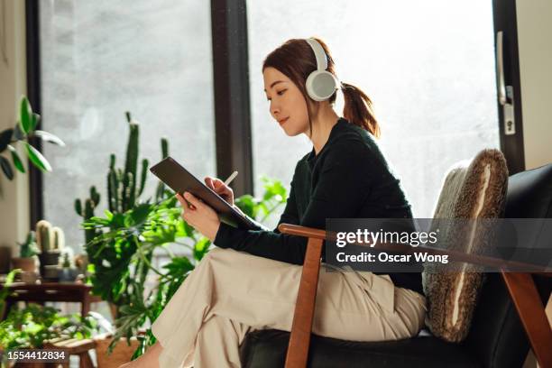 female freelance designer working on digital tablet at a cozy living room - cozy stock pictures, royalty-free photos & images