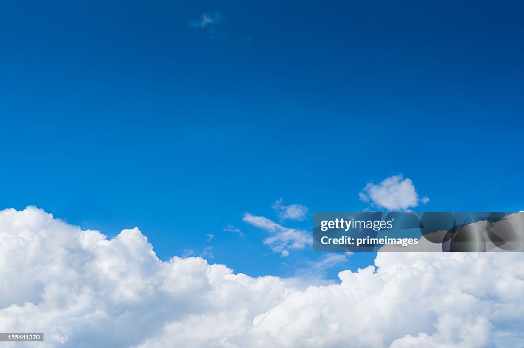 Blue sky with dramatic white clouds below