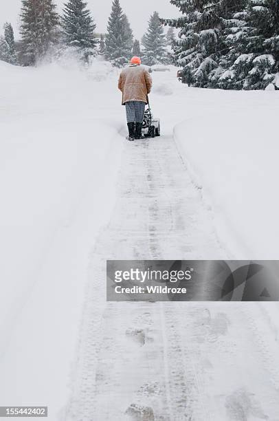 man pushing snow blower in storm - snow blower stock pictures, royalty-free photos & images