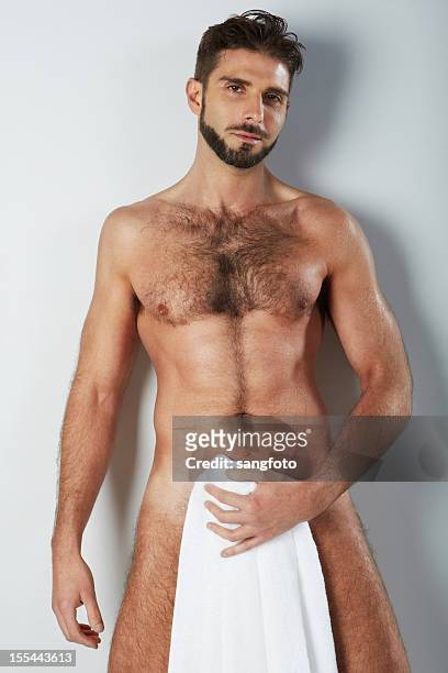 attractive naked hairy man holding bath towel covering smiling - hairy chest man stock pictures, royalty-free photos & images