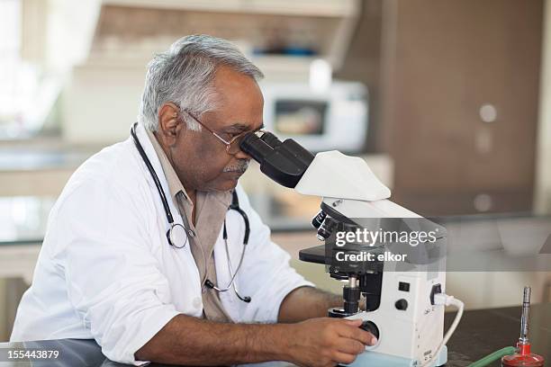 indian doctor using microscope in laboratory - india lab stockfoto's en -beelden