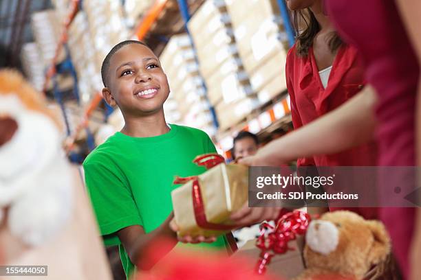 little boy donating christmas present at charity toy donation drive - gift wrap stockfoto's en -beelden