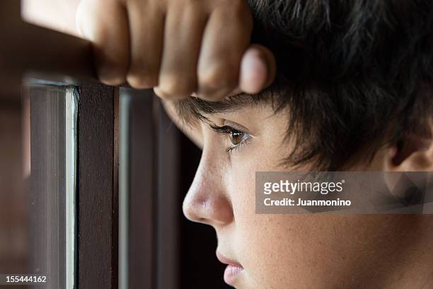 pensive teenager looking through a window - föräldralös bildbanksfoton och bilder