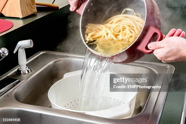 draining fettuccine in a colander - colander stock pictures, royalty-free photos & images