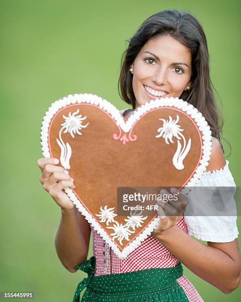woman holding a lebkuchen gingerbread heart with copy space (xxxl) - lebkuchen stock pictures, royalty-free photos & images