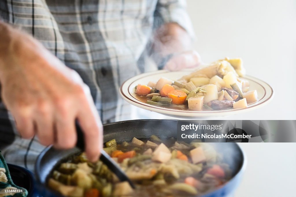 Mann mit einem Teil von Rindfleisch und Gemüse Eintopf