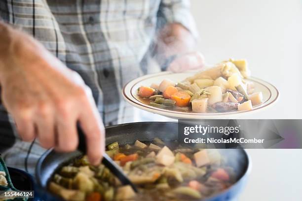 man serving a portion of beef and vegetable stew - stew stock pictures, royalty-free photos & images