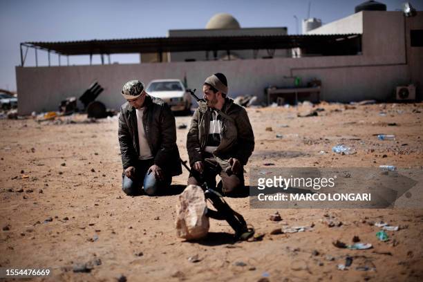 Libyan rebel fighters perform the ritual noon prayer in Ras Lanuf on March 7, 2011 as opposition forces ceded ground to Moamer Kadhafi's advancing...