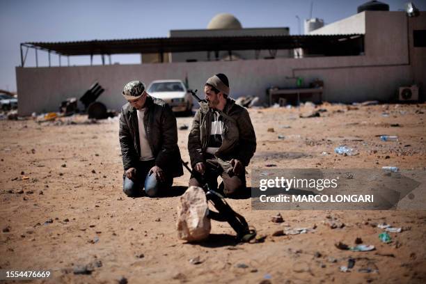 Libyan rebel fighters perform the ritual noon prayer in Ras Lanuf on March 7, 2011 as opposition forces ceded ground to Moamer Kadhafi's advancing...