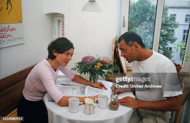 Österreichische Schauspielerin Caroline Grothgar und Kollege Giovanni Arvaneh sitzen bei einem Szenendreh gemeinsam am Küchentisch, Deutschland 1996.