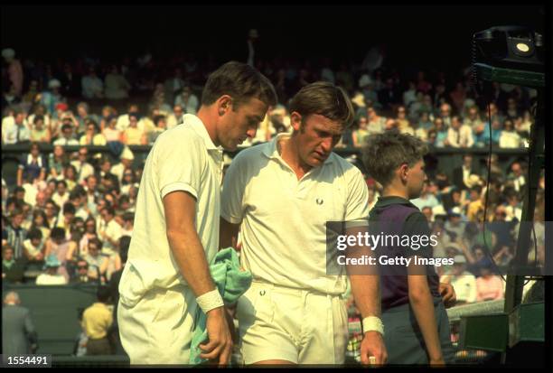 JOHN NEWCOMBE AND TONY ROCHE OF AUSTRALIA DISCUSS TACTICS DURING A BREAK IN A DOUBLES MATCH AT THE WIMBLEDON TENNIS CHAMPIONSHIPS.